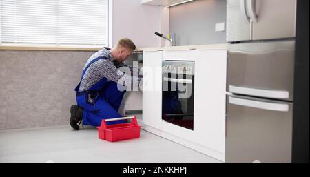Plumber Cleaning Drain And Pipe In Kitchen Stock Photo