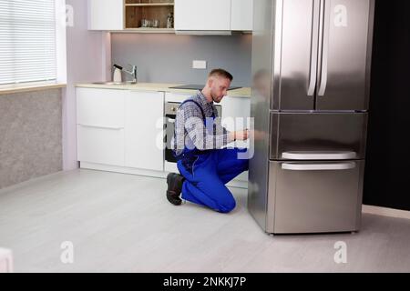 Male Worker Repairing Refrigerator With Screwdriver In House Stock Photo