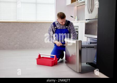 Electrician Technician Working To Repair Refrigerator Or Fridge Appliance Stock Photo