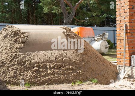 Machine with mixer isinstallation for feeding cement mixture for pouring semi-dry floor screed in house. Construction site with slide of sand, prepara Stock Photo