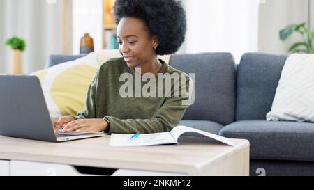 Female student studying using laptop and making notes to prepare for exams or research for college assignment. African woman highlighting information Stock Photo