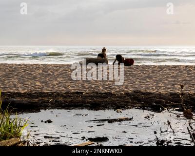 A young couple relax on the beach as the waves wash in near Nosara in Costa Rica Stock Photo