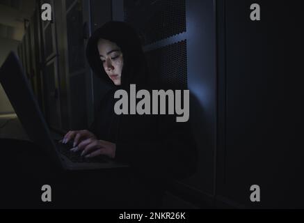 Hacking, server room and woman computer coding, data center crime and ransomware of cyberpunk in dark. Laptop hacker, person or thief in cybersecurity Stock Photo