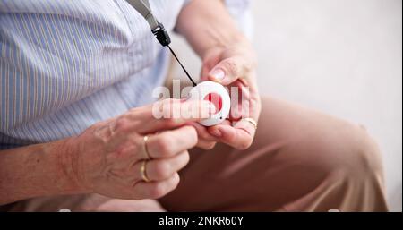 Senior Woman Pressing Alarm Button For Emergency Stock Photo