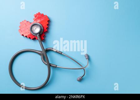 stethoscope standing on red heart on blue background Stock Photo