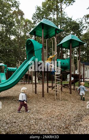 Children playing on climbing frame in play park Stock Photo