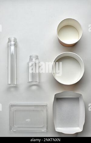Various disposable tableware bottles and containers on a white background. Vertical Stock Photo