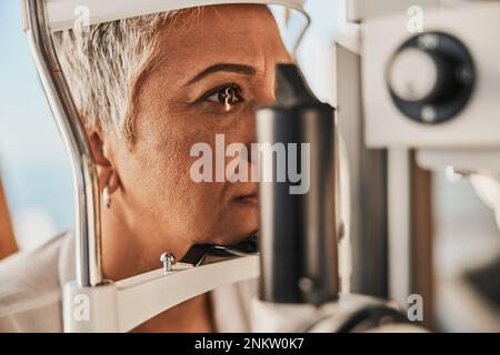 Medical, ophthalmology and eye test by patient senior woman with medical insurance using slit lamp. Mature, optometry and female doing vision or Stock Photo