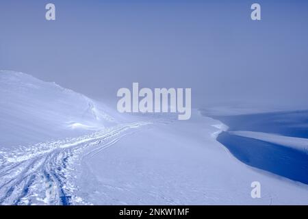 Traces of ski mountaineers disappearing into the fog in Swiss Alps Stock Photo