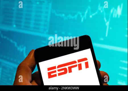 China. 15th Feb, 2023. In this photo illustration, the American sports media conglomerate majority-owned by The Walt Disney Company, ESPN, logo is seen displayed on a smartphone with an economic stock exchange index graph in the background. Credit: SOPA Images Limited/Alamy Live News Stock Photo