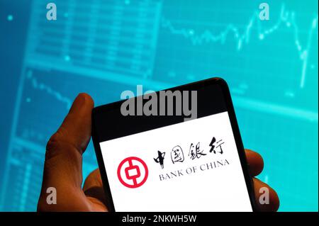 In this photo illustration, the Chinese state-owned commercial banking company Bank of China logo is seen displayed on a smartphone with an economic stock exchange index graph in the background. (Photo by Budrul Chukrut / SOPA Images/Sipa USA) Stock Photo