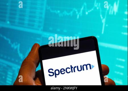 China. 15th Feb, 2023. In this photo illustration, the American telecommunications company Spectrum logo is seen displayed on a smartphone with an economic stock exchange index graph in the background. (Photo by Budrul Chukrut/SOPA Images/Sipa USA) Credit: Sipa USA/Alamy Live News Stock Photo