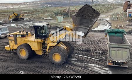 Huge Wheel Loader Loading Coal On Trucks, Coal Mine. Stock Photo