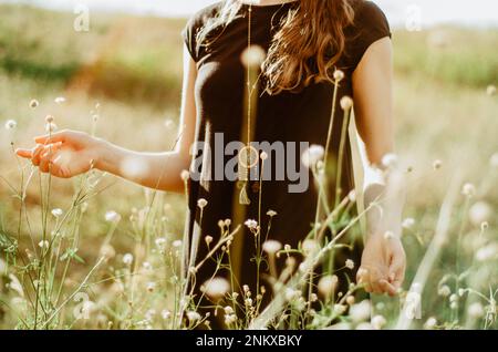 Mid section boho styled woman walking among wildflowers Stock Photo