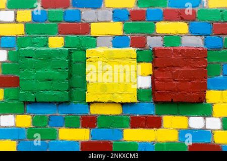 Brick wall with painted white, grey, blue, green, red, yellow bricks and large green, yellow, red squares. Stock Photo