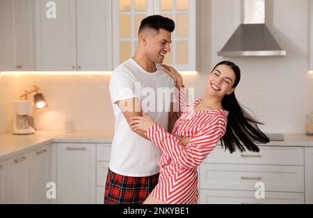 Happy couple wearing pyjamas and dancing in kitchen Stock Photo