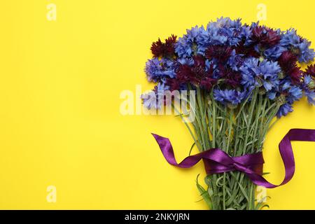 Bouquet of beautiful colorful cornflowers on yellow background, top view. Space for text Stock Photo