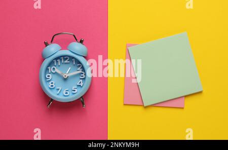 Alarm clock and blank reminder notes on color background, flat lay Stock Photo