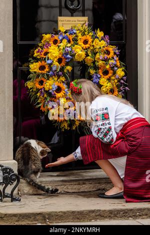 Downing Street, London, UK. 24th February 2023.  Ukranian lady in traditional costume with Larry the Cat on the doorstep of number 10 Downing Street following a minute’s silence to mark the one-year anniversary of the full-scale Russian invasion of Ukraine. Photo by Amanda Rose/Alamy Live News Stock Photo