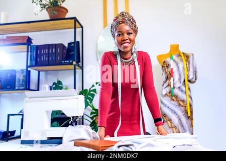 tanzanian woman with snake print turban over hear working in dressmaking shop Stock Photo