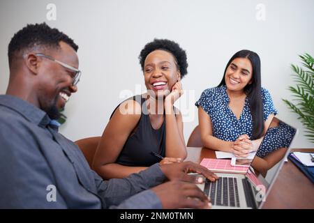 Three diverse colleagues laugh and joke in the workplace, friendly meeting Stock Photo