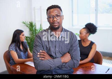 Portrait of a serious Black businessman with arms folded, boardroom colleagues Stock Photo