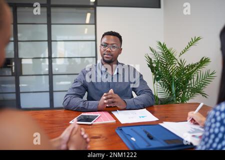 Black businessman listens to clients during meeting in boardroom Stock Photo