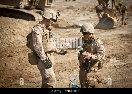 The corpsman for Bridge Platoon, Alpha Company, 9th Engineer Support Battalion, gives some aspirin to a soldier during the construction of a bridge in the district of Garmsir, Helmand province ca. possibly 2012 Stock Photo