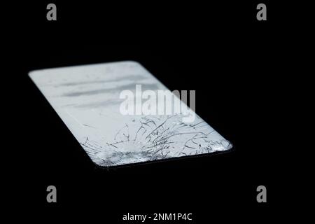 Mobile phone with broken glass and white screen in the darkness Stock Photo