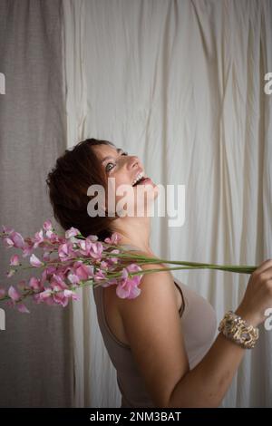 happy, beautiful woman in profile, laughing joyfully, a blooming spring twig on her shoulder. elegant business woman celebrating triumph, good news. P Stock Photo