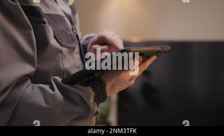 Close up shot of installer sets up security camera in house using digital tablet computer and app. Worker checks internet speed after installation. Installation of wireless local area network. WLAN. Stock Photo