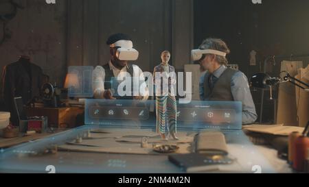 Two multi ethnic tailors in VR headsets in atelier. 3D female hologram of garment pattern. Virtual interface menu of program for designing and modeling clothes. Concept of AR modern technologies. Stock Photo