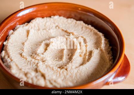 Home made hummus in a bowl on a wooden table Stock Photo