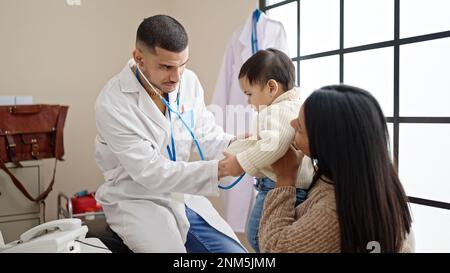 Couple and son examining baby with stethoscope at clinic Stock Photo