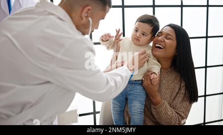 Couple and son examining baby with stethoscope at clinic Stock Photo