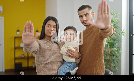 Couple and son hugging each other doing stop gesture at home Stock Photo