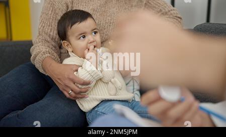 Couple and son examining baby with stethoscope at clinic Stock Photo