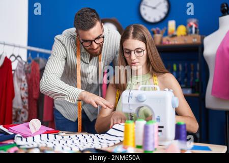 Man and woman tailors smiling confident using sewing machine at clothing factory Stock Photo