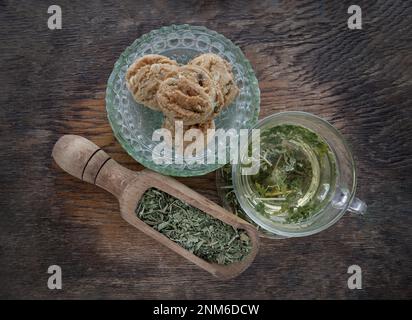 Refreshing and Enjoy with A cup of hot hemp tea (CBD herbal tea) and Dried organic hemp leaves served with Scones on old rustic wooden background. Hea Stock Photo