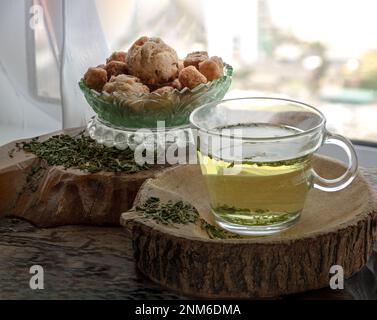 Refreshing and Enjoy with A cup of Hot Hemp Tea (CBD herbal tea) served with Scones and Croutons on old rustic wooden table by the window view with su Stock Photo