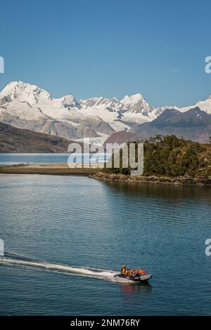 Cordillera Darwin and explorers riding a zodiac, in Ainsworth Bay, PN Alberto de Agostini, Tierra del Fuego, Patagonia, Chile Stock Photo