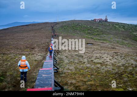 Explorers walking to lighthouse, Cape Horn, Tierra de Fuego, Patagonia, Chile Stock Photo