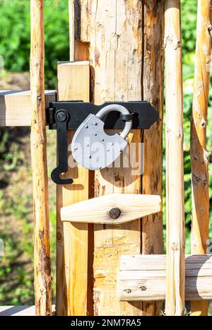 New metal padlock on a bright yellow wooden fence in the village Stock Photo