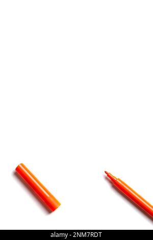 An orange felt-tip pen with a cap lies on a white background. empty space for writing Stock Photo