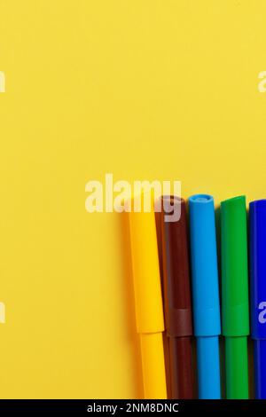 Markers of different colors on a yellow background. Stock Photo