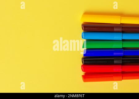 Markers of different colors on a yellow background. Stock Photo