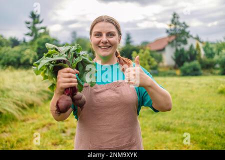 Farmer woman holding a bunch of freshly harvested beetroots and a garden spade Stock Photo