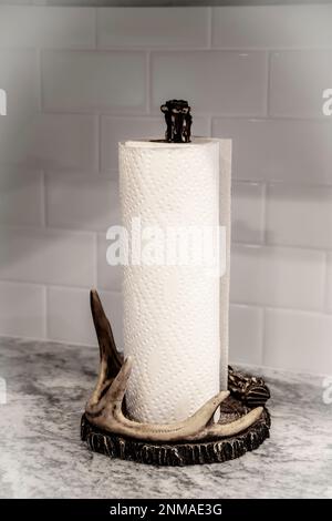 A paper towl roll on a dear horn holder sitting on a marble counter with white tiles behind Stock Photo
