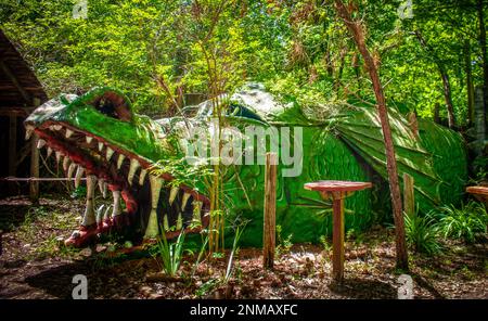 Green scaly dragon in woody park where children can play inside Stock Photo