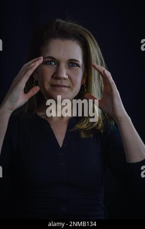 portrait of a beautiful blonde woman who with a gesture of her hands says she is full of work Stock Photo